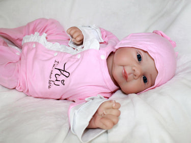 A baby doll lying on a pristine white sheet, emphasizing its adorable appearance and gentle colors.